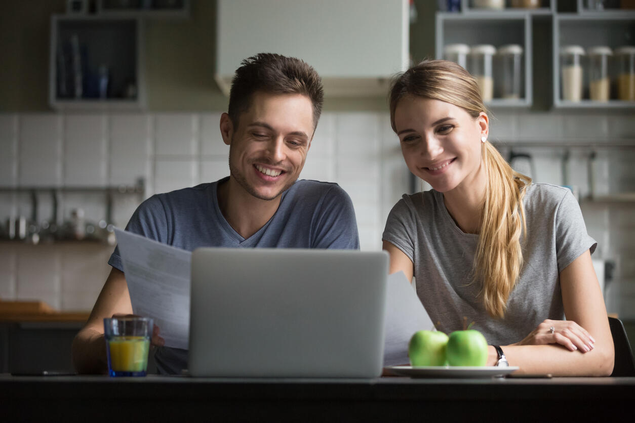 Fornøyd par foran laptopen når de ser hvor mye de kan spare